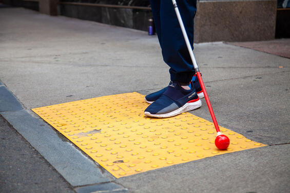 Man standing on a sidewalk with his white cane