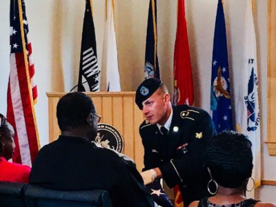 Image of a military personel giving the burial flag to family memeber 