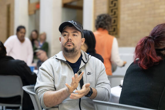 A seated man in a gray sweatshirt clapping during the ceremony.