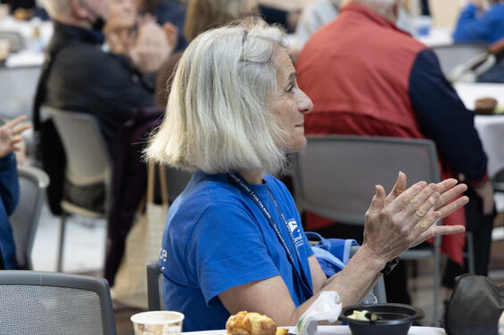 A woman in a blue t-shirt clapping her hands during the ceremony.
