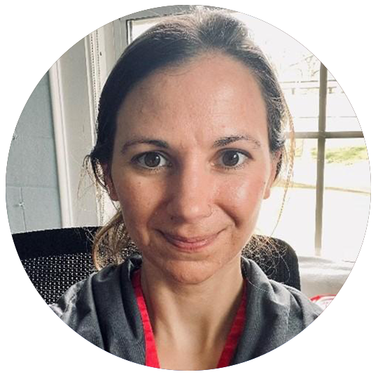 Jamie Moore is a registered nurse. She ties her hair back and smiling at the camera. She has a dark-colored windbreaker on.
