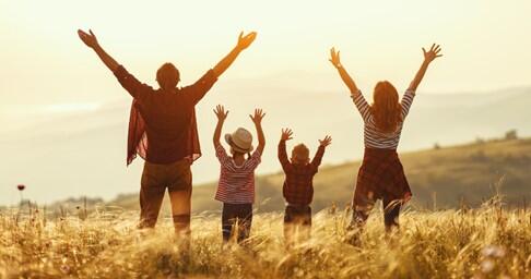 Family on a mountain with their arms in the air