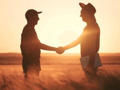 Farmers shaking hands with outreach worker