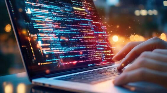 A person types on a laptop, displaying colorful code and software development in a vibrant nighttime setting.