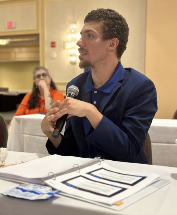 Cody Rooney sitting at a table speaking into a microphone.