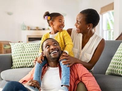 A picture containing a family of three, sitting indoor, smiling