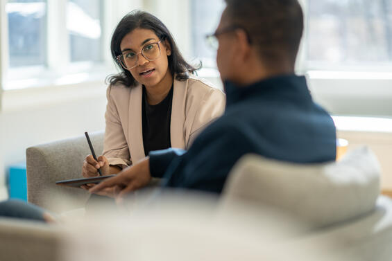 Two people in conversation, with one person speaking and the other taking notes.