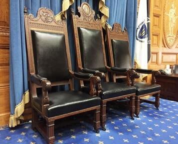 Three mahogany and leather chairs on the rostrum of the House Chamber