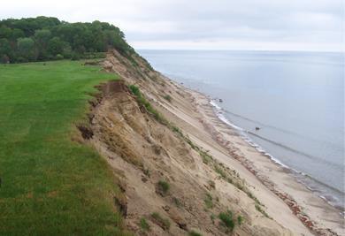 A property with a lawn directly adjacent to an eroding coastal bank.