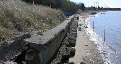 A failing vertical seawall that is being undermined and is failing.