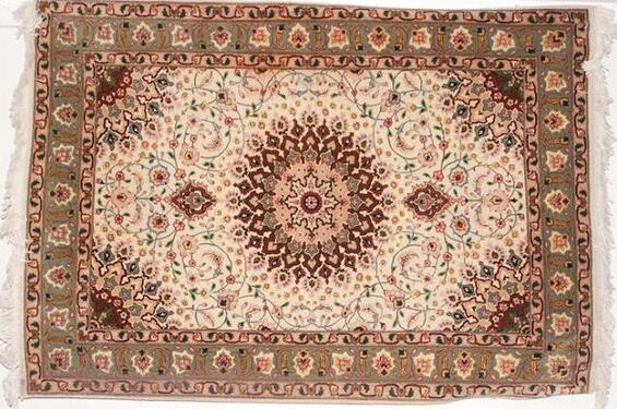 A traditional Tabriz rug, ornately patterned with red, brown, beige and green flowers, vines, and suns