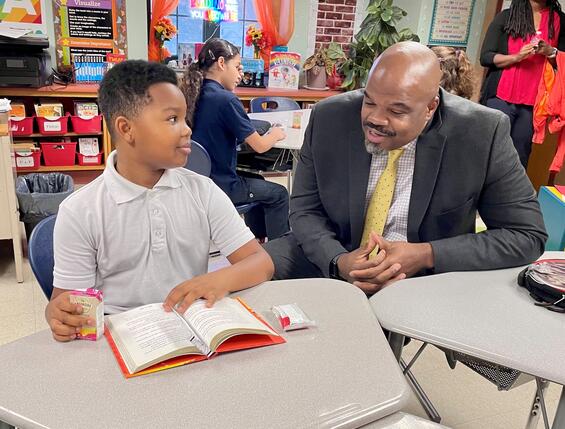 Secretary Tutwiler speaks with a Springfield elementary student during breakfast. Both are sitting down at a classroom table.
