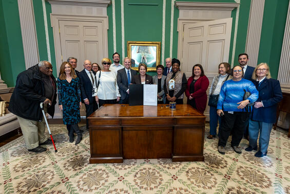 Group of people posing behind the Governor's desk 
