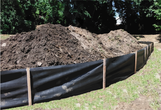 A silt fence held up by wooden stakes surrounds a large pile of soil