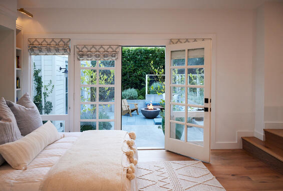 A bedroom with double doors looking out on a patio