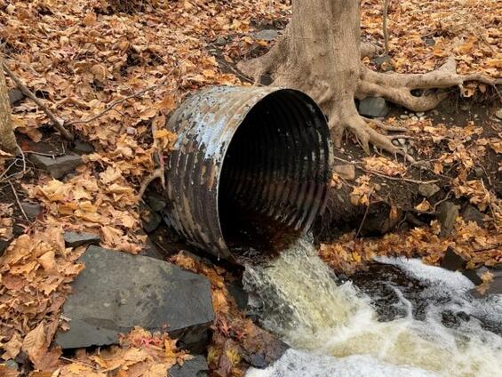 a corrugated metal pipe culvert in poor condition releasing storm water into a creek