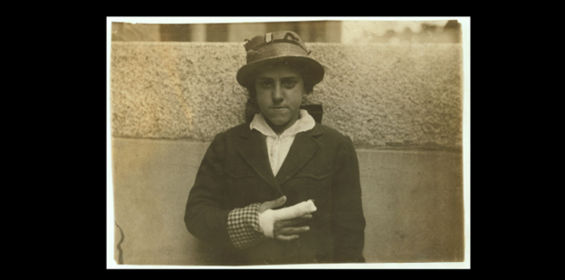 A young person, Estelle Poiriere, standing, wearing a hat and coat, with her right hand heavily bandaged.