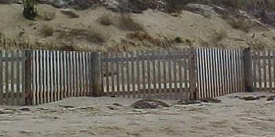 Heavy and solid-wood fence in a zigzag pattern in front of a dune