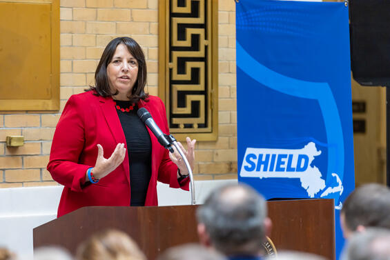 Lt. Governor Kim Driscoll at a Podium with the Shield logo behind her
