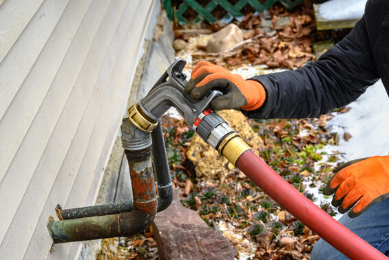 A worker pumps heating oil into a home. 