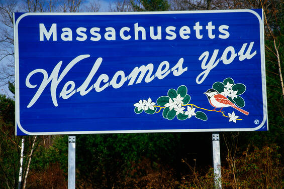 A Massachusetts welcomes you road sign with a chickadee on it