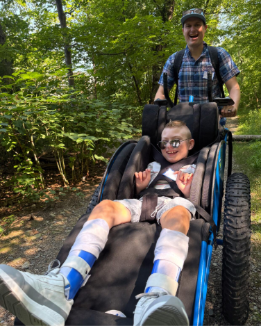Young person on park trail in adaptive wheelchair