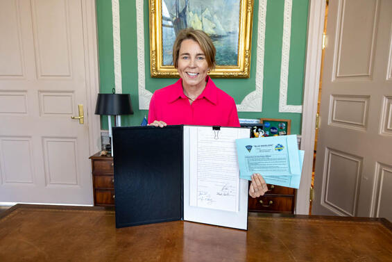 governor healey with a signed bill and a blue envelope