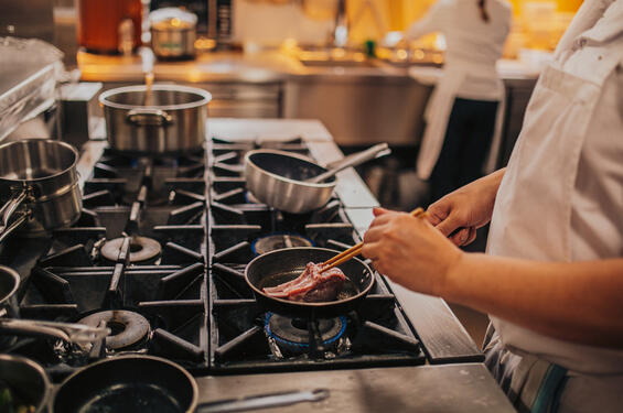 Chef cooking with various pots and pans