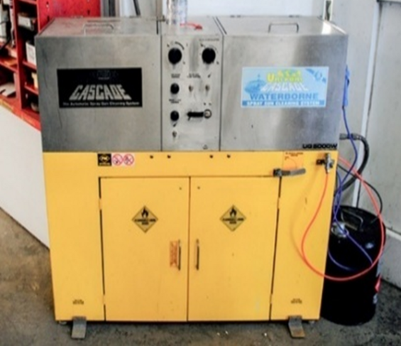 Metal spray gun cleaning station in an automotive paint shop with two cleaning tanks, one for solvent-based paint and one for water-based paint.