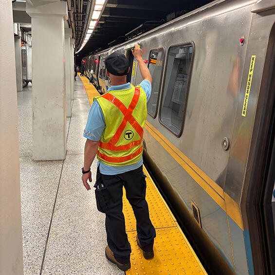 MBTA official in a yellow and orange safety vest clears a train for departure at Government Center
