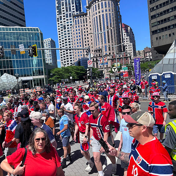 Excited fans in red and blue soccer jerseys wait outside South Station.