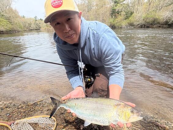 An angler holding up a fish he just caught in the river.