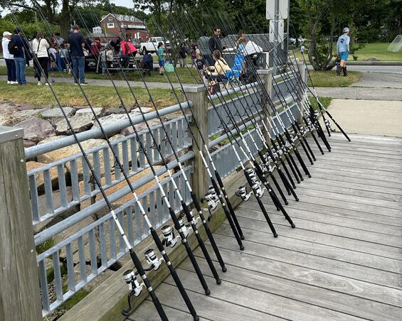 Saltwater fishing rods lined up on along a pier railing.