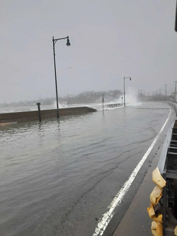 Waves crash across a flooded Winthrop Parkway during a storm event