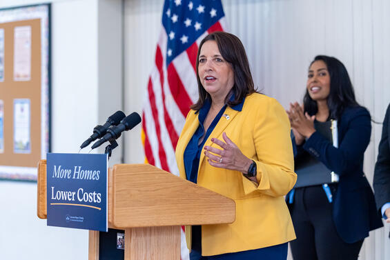 Lieutenant Governor Kim Driscoll stands at a podium with Secretary Matias and an American flag behind her. 