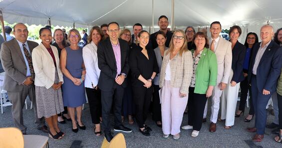 A group of state legislators, Healey-Driscoll Administration officials and grant recipients stand for a group photo under a large white tent.