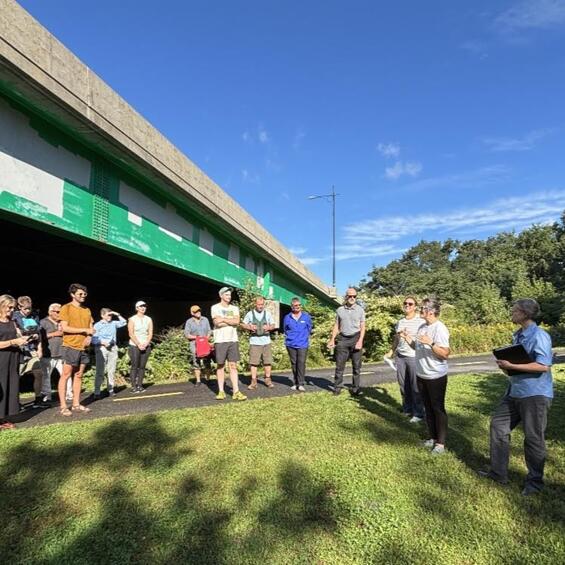 People standing in a line listening to someone speak.