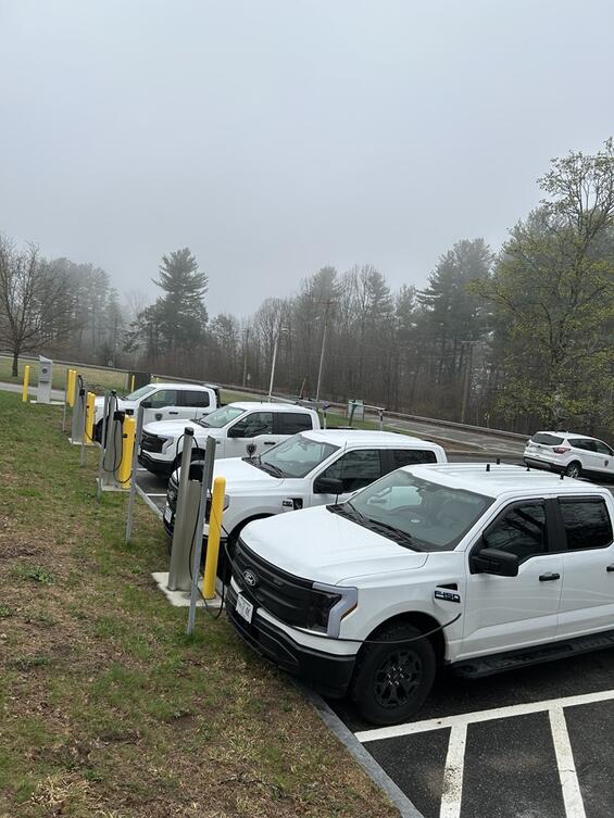 Electric vehicles plugged into charging stations at a DCR parking lot