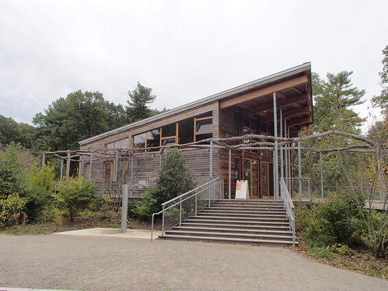 A visitor center with wooden facade and natural wooden beams surrounded by native plants