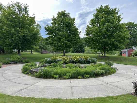A flower garden surrounded by a walkway in a city park
