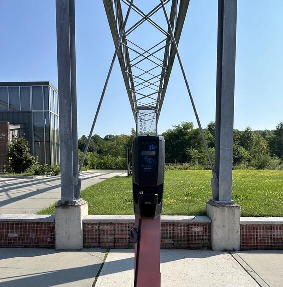 An electric vehicle chaging station on a sidewalk with a visitor center in the background 