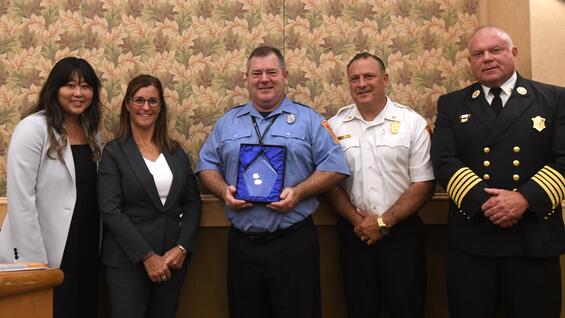 Firefighter Peter Reardon holding the Educator of the Year Award with local and state officials