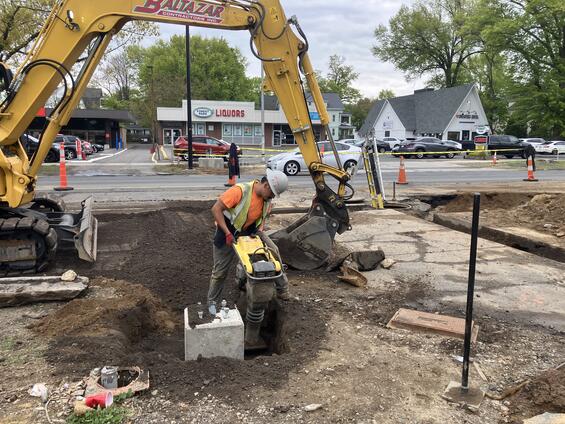 Construction worker tamping ground at light base