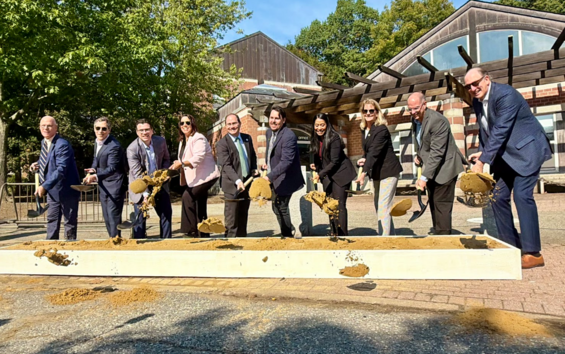 Officials pose with shovels behind a pile of dirt