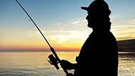 A man fishing at sunset.