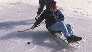 Man playing ice hockey on his seated ice skating chair.