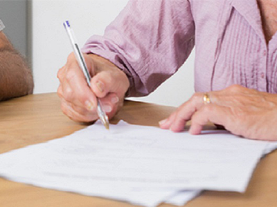 A person using a pen to sign forms.