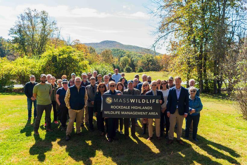 landscape view of WMA with people standing behind WMA sign