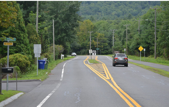 Two lane road widening out with grass median in center