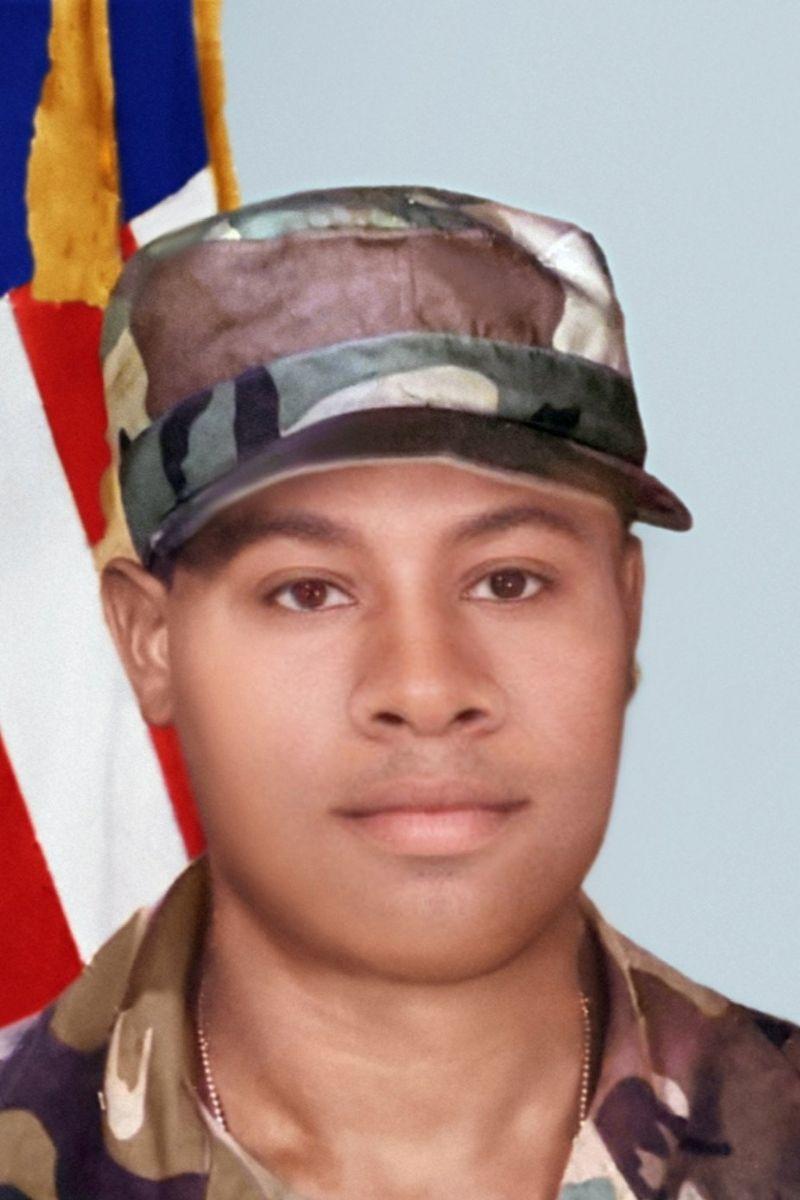 Headshot of Alvin Calderon in army fatigues in front of American flag